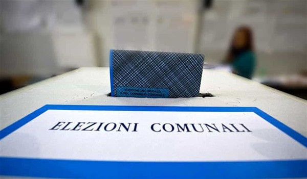Si rappresenta un'urna elettorale, dove viene inserita una scheda elettorale. La scritta indica "ELEZIONI COMUNALI".